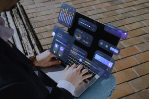 homem trabalhando sentando com um notebook no colo, algumas imagens hologramas de graficos estão saindo da tela, é um capa para o artigo melhores sistemas contabeis de 2025 da ottimizza.